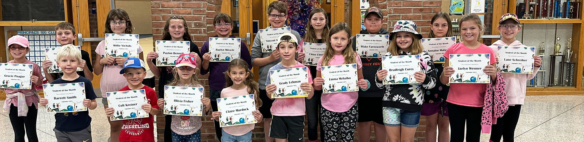 Group of happy elementary students holding up certificates