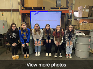 Students posing in front of large screen in a warehouse