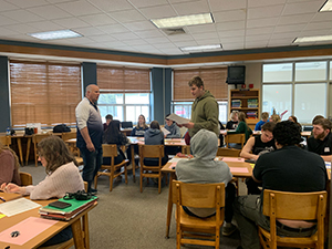 Two adults standing in classroom with students playing synchronous game
