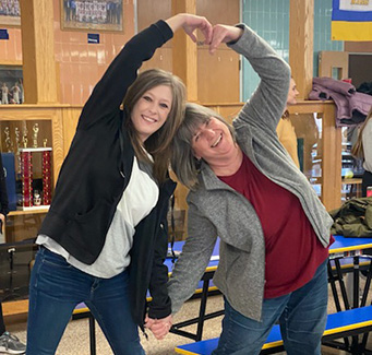 Two ladies making a heart pose with their arms